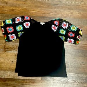 Black shirt with crochet design on sleeves.